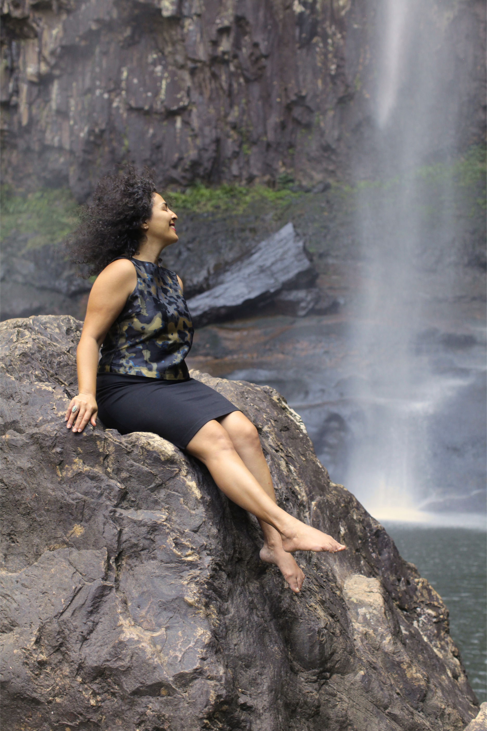 Woman sitting in nature next to a waterfall