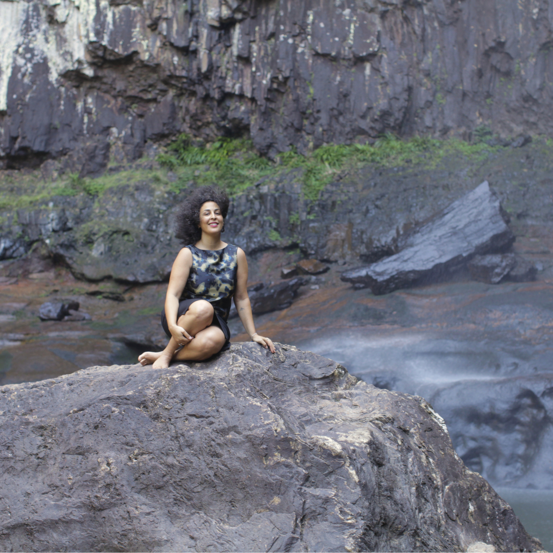 Woman sitting in nature next to waterfall